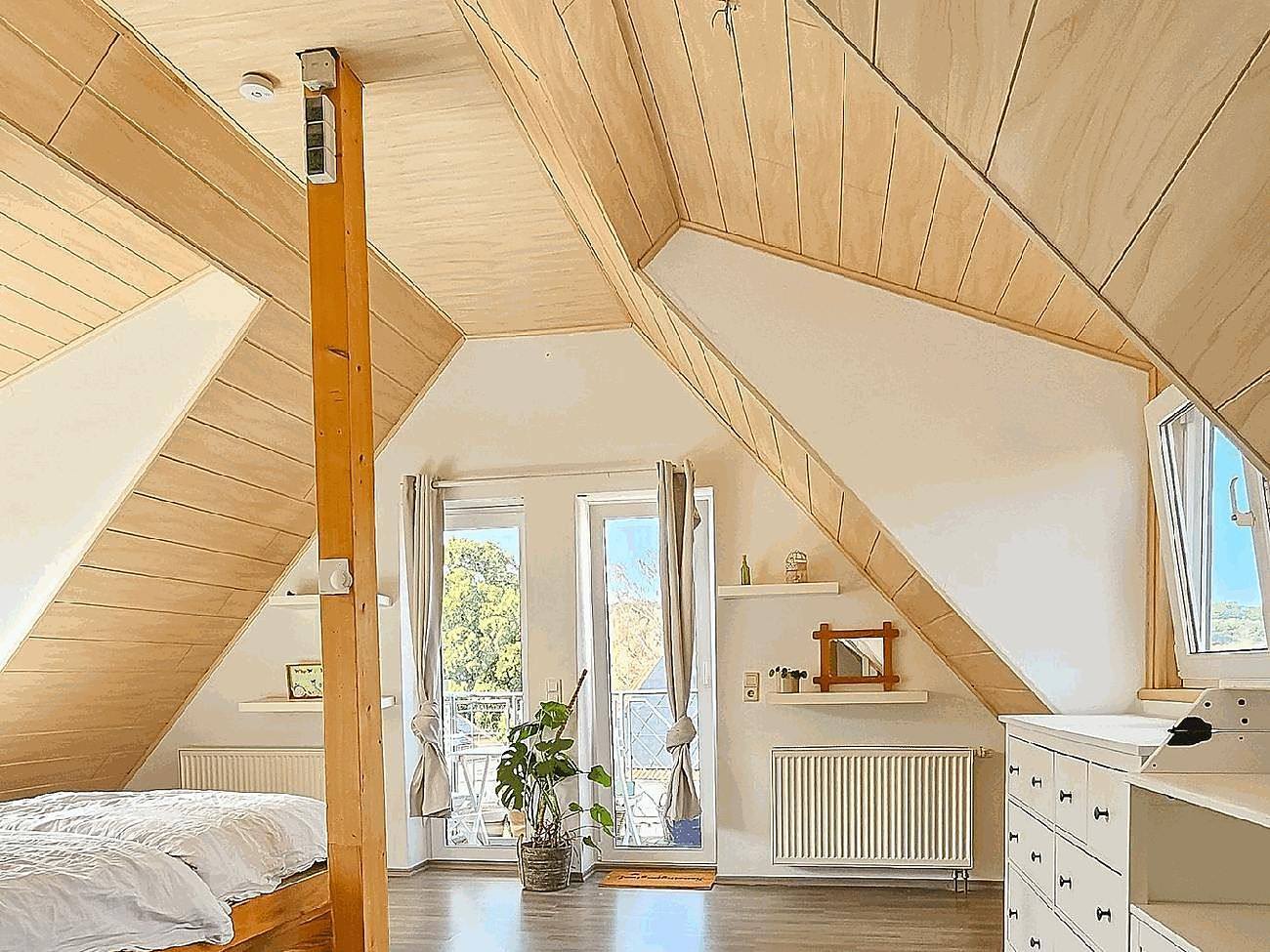 Schlafzimmer mit Holzschrägen und Balkonzugang