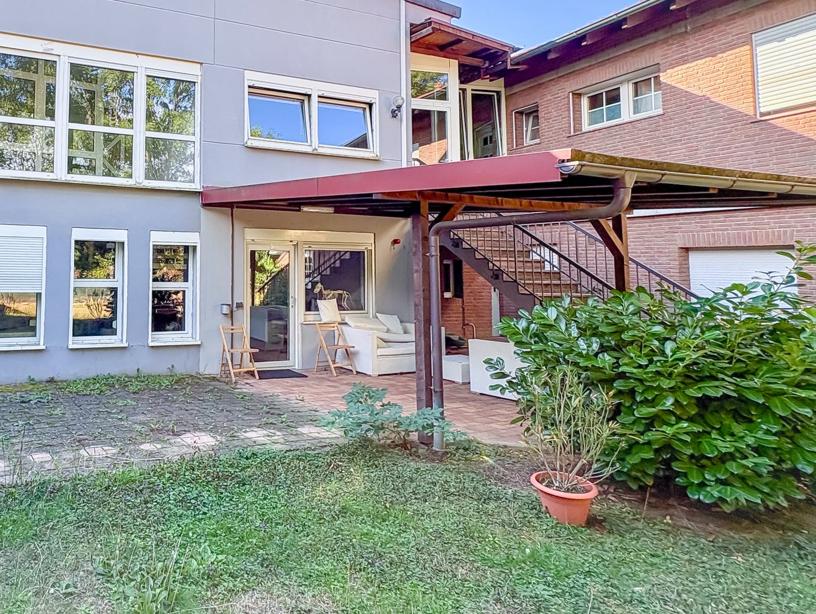 Überdachte Terrasse am Gebäude mit Garten
